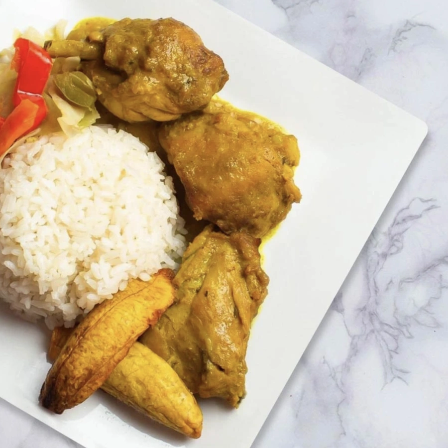 Square plate on a white background accompanied by chicken in sauce