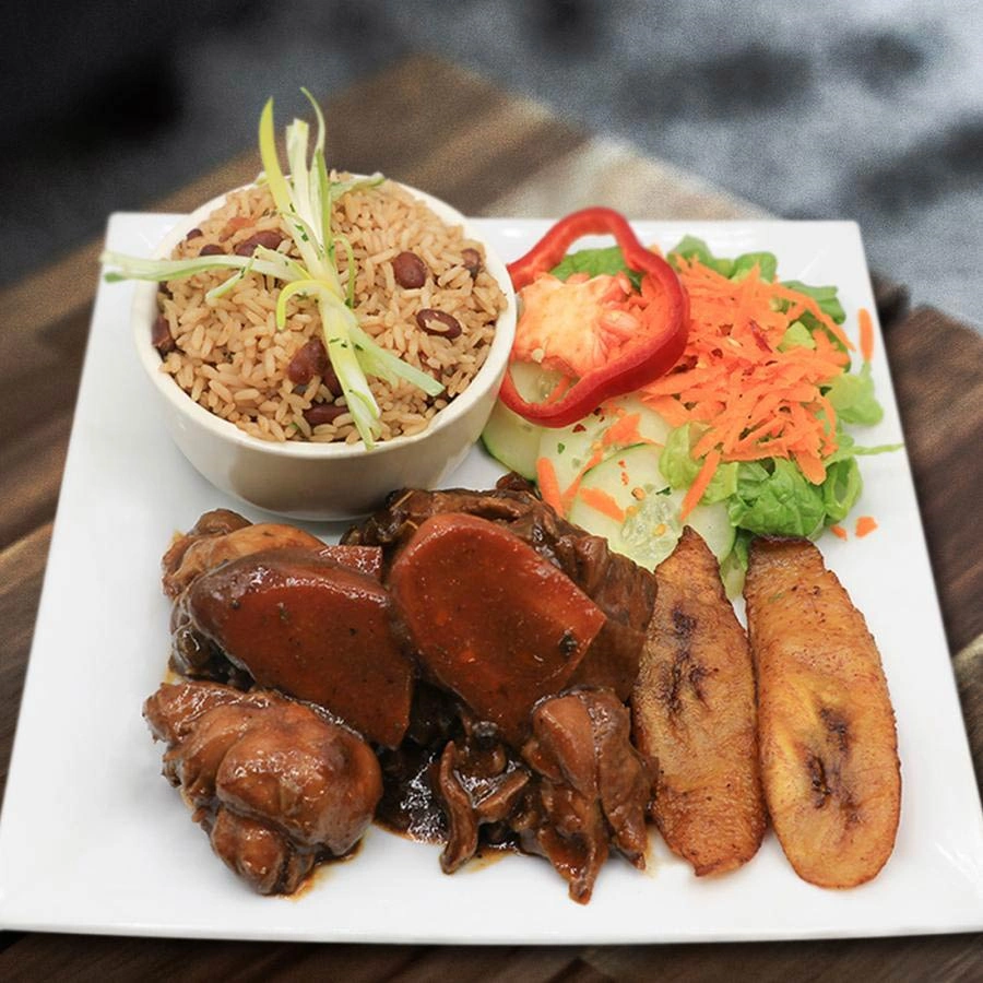 Meat in sauce and vegetables with side of rice and beans