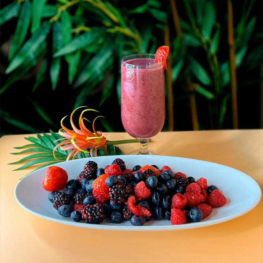 Blackberry juice with pieces of strawberry and a side of red fruits